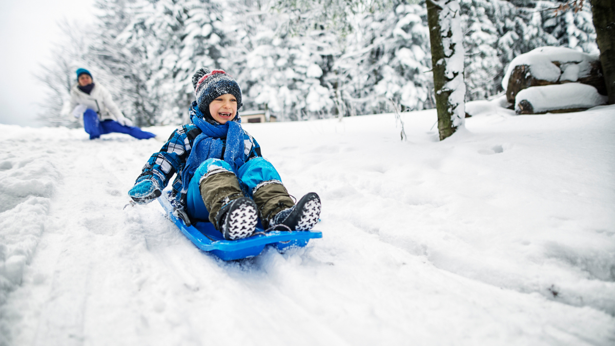 Un jeune profite d’une glissade en hiver